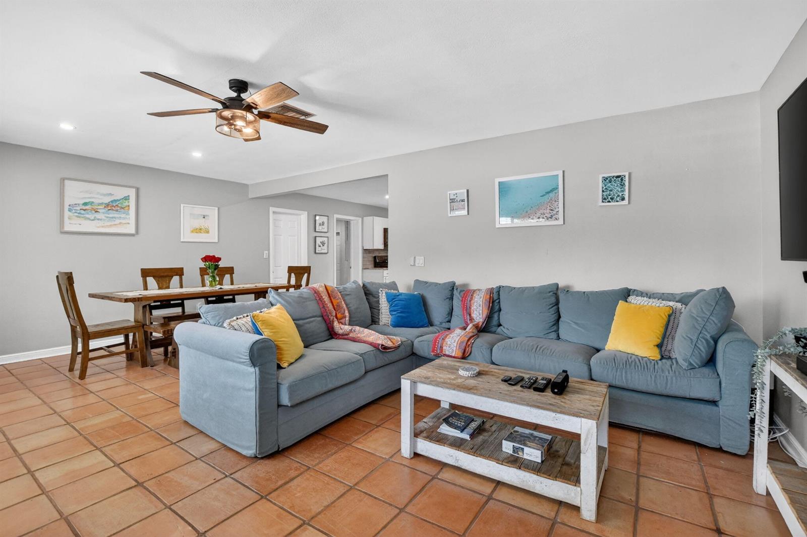 A living room with a large blue sectional sofa, a wooden coffee table, and tile flooring — 721 NE 8th Avenue, Boynton Beach FL 33435, BOYNTON BEACH, FL