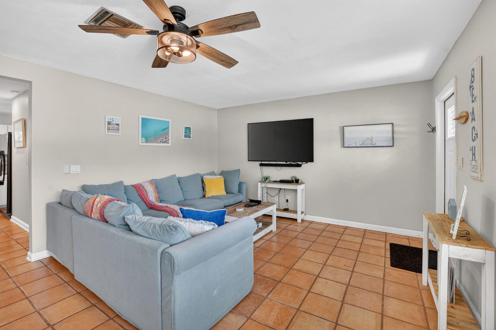 A living room features a blue sectional sofa, a ceiling fan, and terracotta tile flooring — 721 NE 8th Avenue, Boynton Beach FL 33435, BOYNTON BEACH, FL