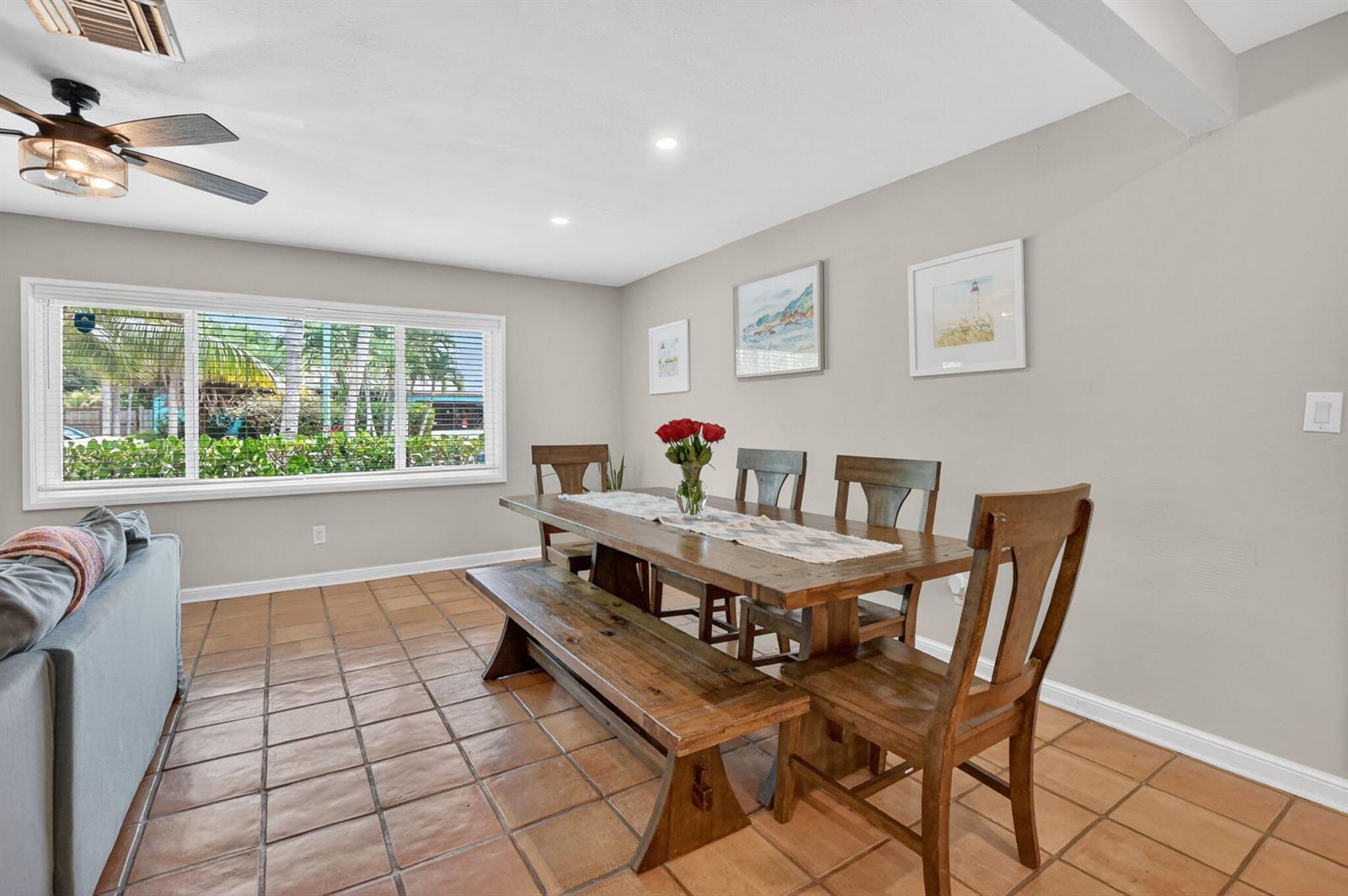 A dining room features a wooden table with a bench and chairs on tile flooring — 721 NE 8th Avenue, Boynton Beach FL 33435, BOYNTON BEACH, FL