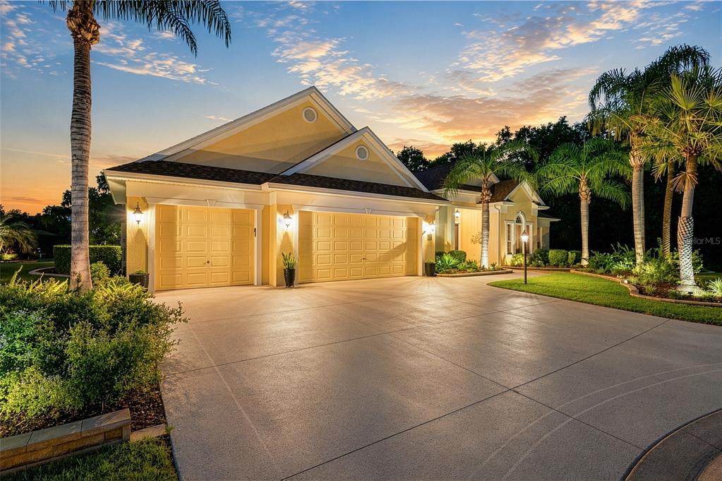 A yellow house with a three-car garage and palm trees at sunset — 2063 LAKE RIDGE DRIVE, THE VILLAGES, FL