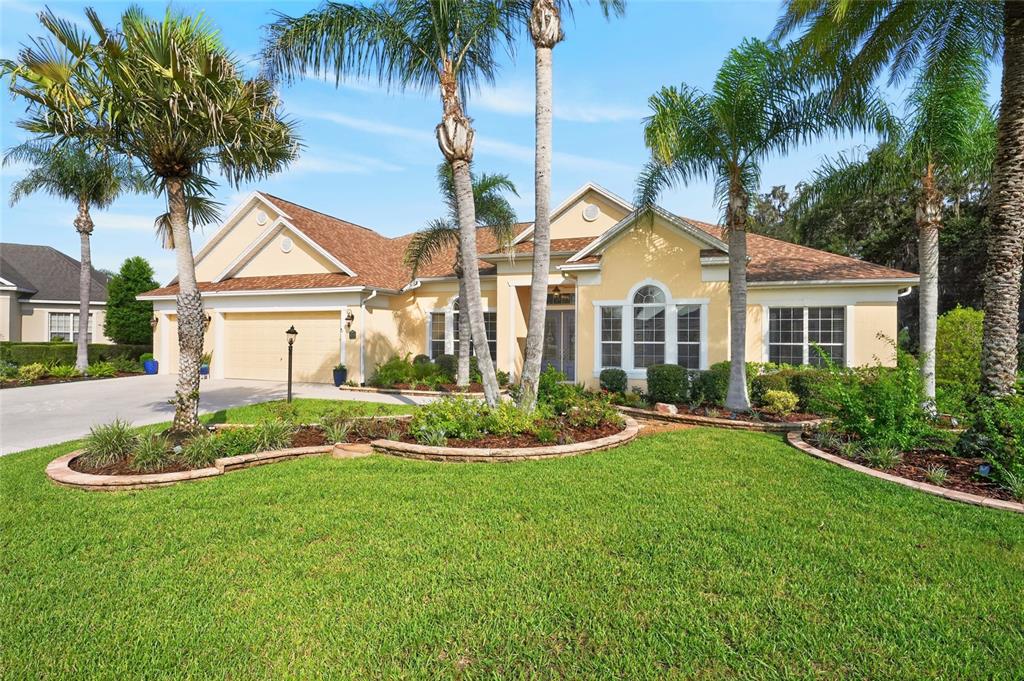 A single-story yellow house with a two-car garage and palm trees in the front yard — 2063 LAKE RIDGE DRIVE, THE VILLAGES, FL