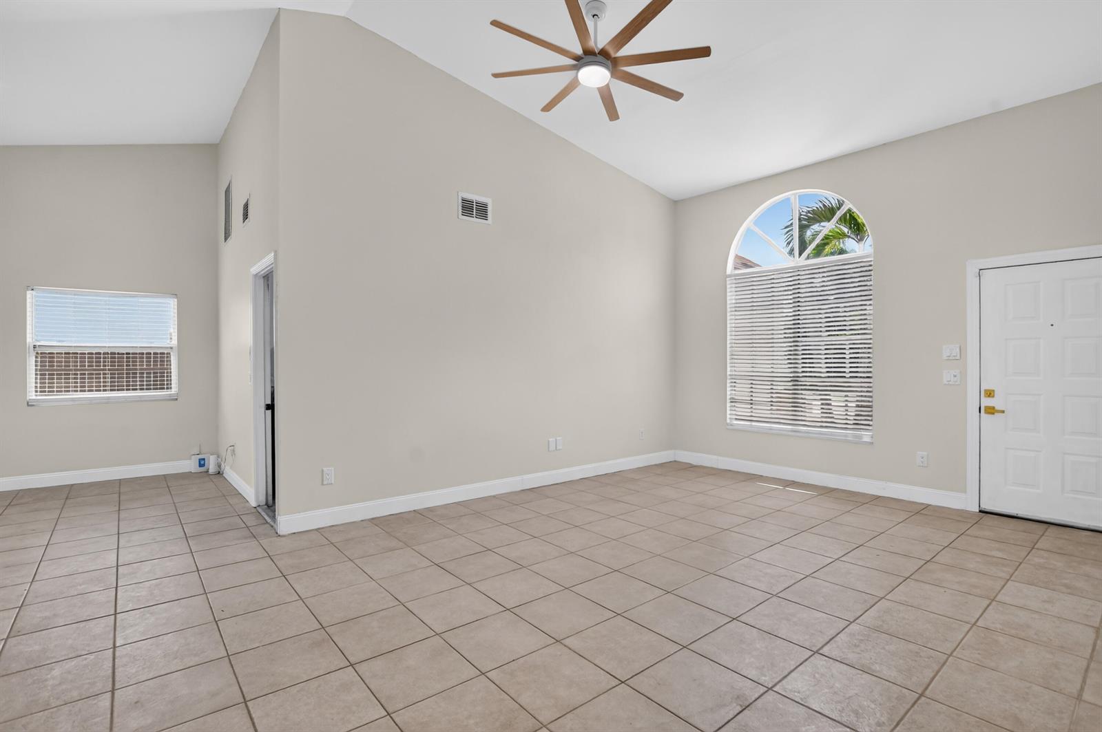 An empty room with vaulted ceilings, tile floors, a ceiling fan, and arched windows — 23172 Bentley Place, Boca Raton FL 33433, BOCA RATON, FL