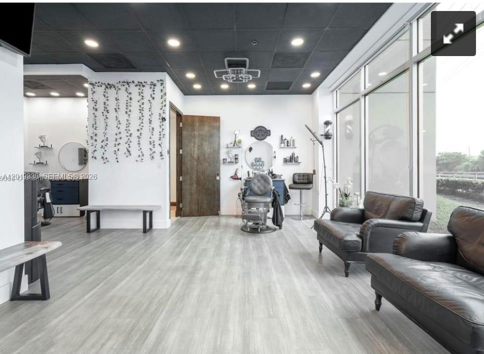 A modern barbershop interior features a black drop ceiling, wood-look flooring, and large floor-to-ceiling windows — 2300 W 84th St, Hialeah FL 33016, HIALEAH, FL