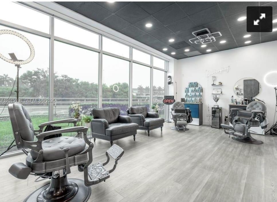A modern barbershop with large windows, gray flooring, a dark ceiling, and multiple styling chairs — 2300 W 84th St, Hialeah FL 33016, HIALEAH, FL
