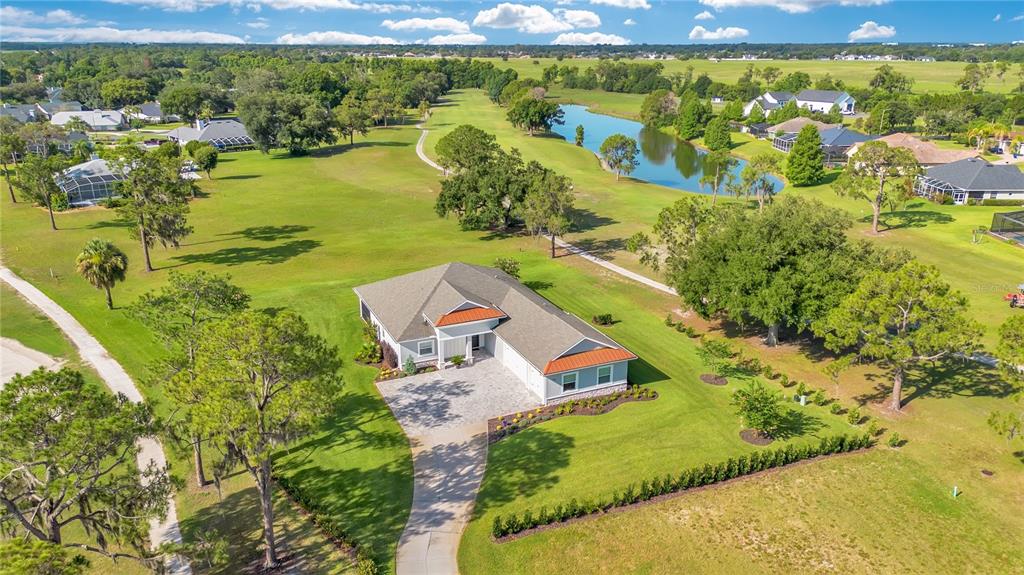 An aerial view shows a single-story house with a paved driveway surrounded by green lawns — 440 PALMA CEIA ROAD, WINTER HAVEN, FL