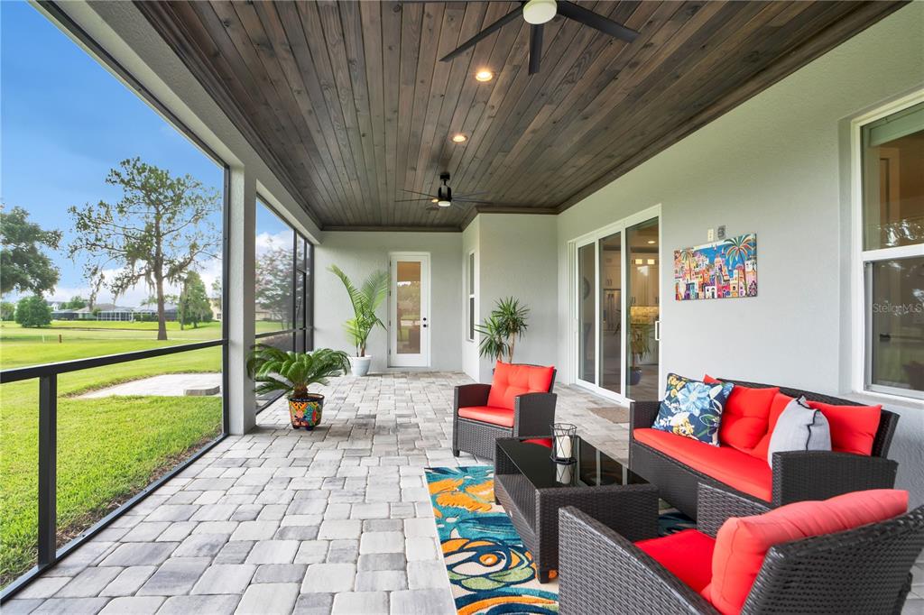 A screened-in patio features a wood-paneled ceiling, stone paver flooring, and outdoor wicker furniture — 440 PALMA CEIA ROAD, WINTER HAVEN, FL