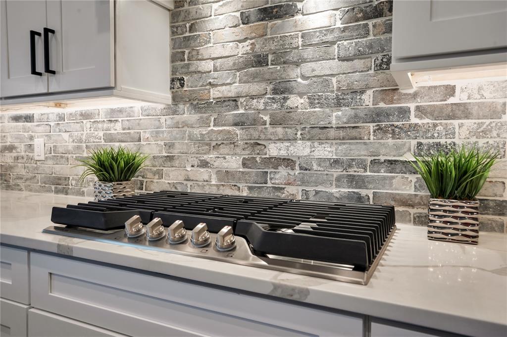 A kitchen cooktop sits on a white countertop against a rustic brick backsplash — 440 PALMA CEIA ROAD, WINTER HAVEN, FL