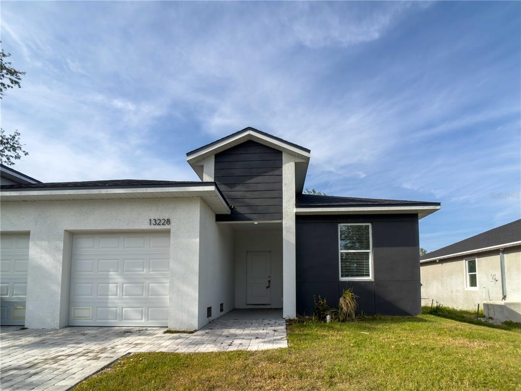 The exterior of a modern, two-tone stucco house features a single-car garage and a paved walkway — 13228 BLYTHEVILLE AVENUE AVENUE, PORT CHARLOTTE, FL