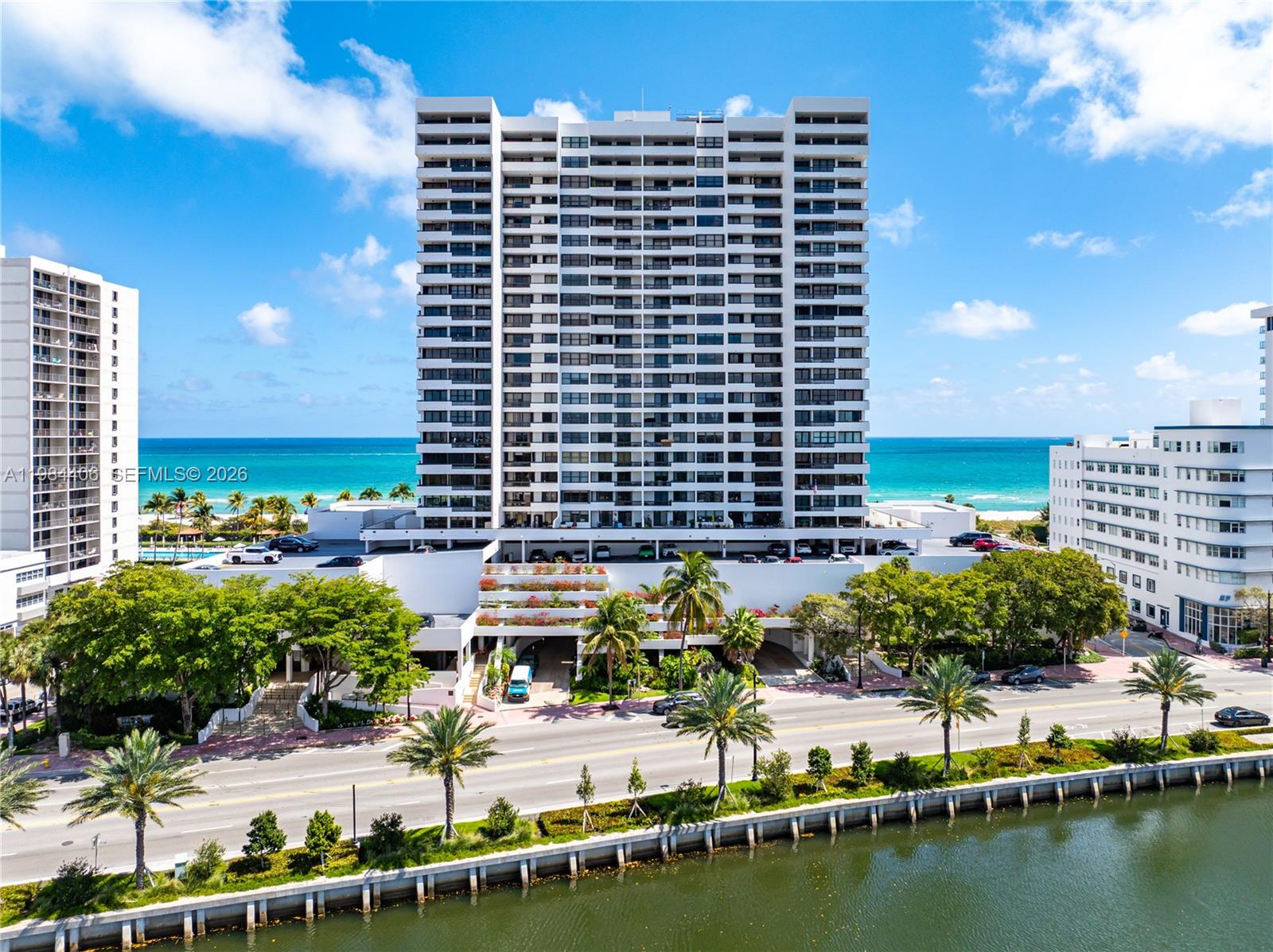 An exterior view of a tall residential building situated between a road and the ocean — 2555 Collins Ave # 2402, Miami Beach FL 33140, MIAMI BEACH, FL