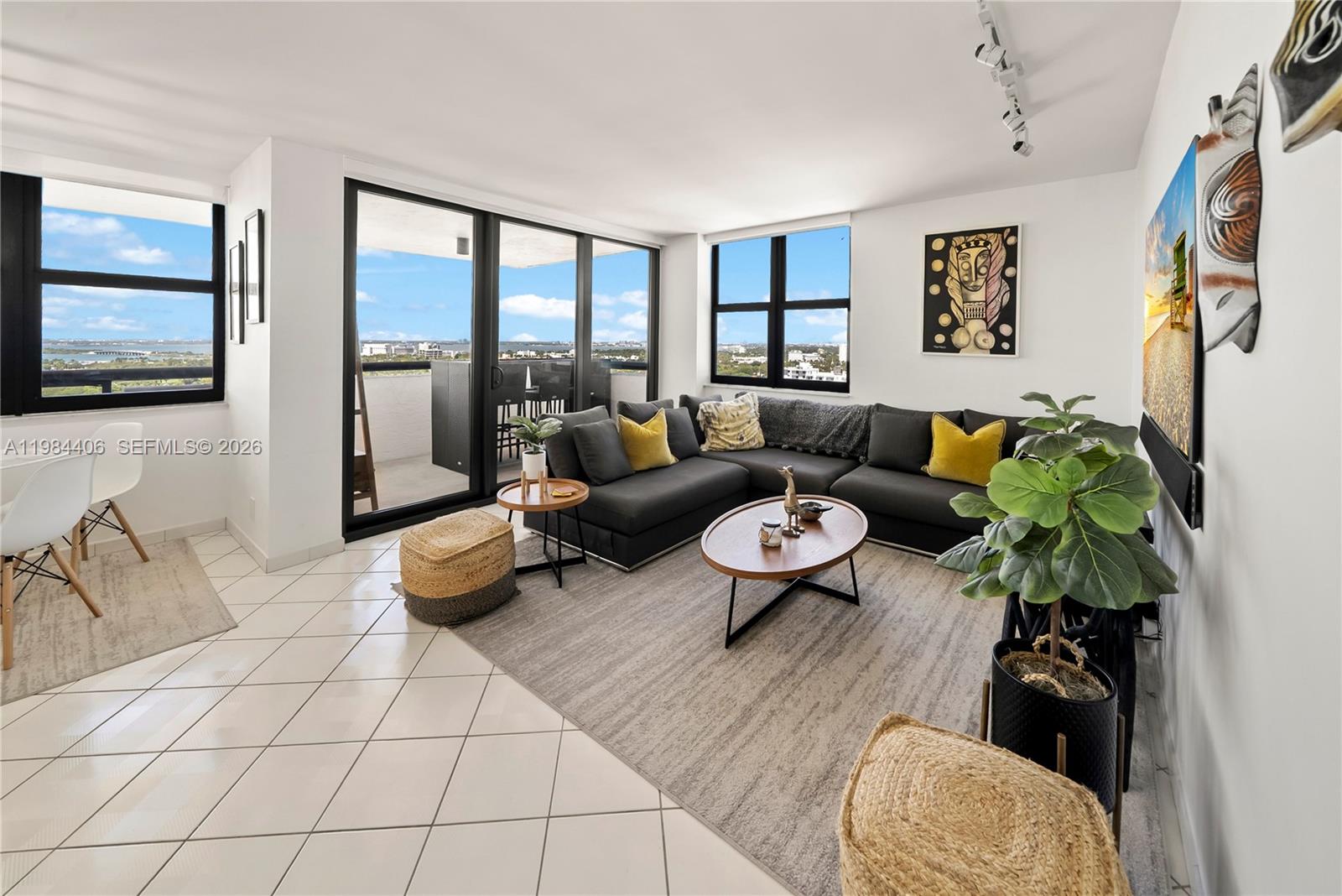 A living room features a dark sectional sofa, a coffee table, and a balcony view — 2555 Collins Ave # 2402, Miami Beach FL 33140, MIAMI BEACH, FL
