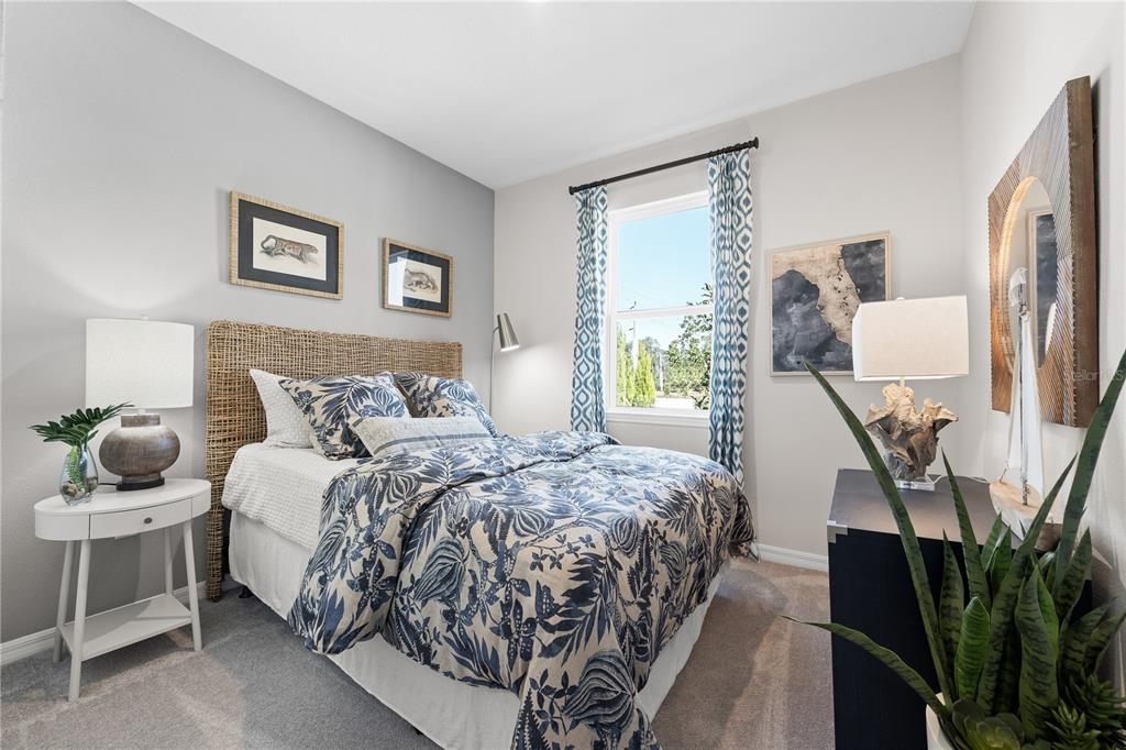 A bedroom with a woven headboard, patterned bedding, and a window with blue curtains — 1710 FLAG STREET, HAINES CITY, FL
