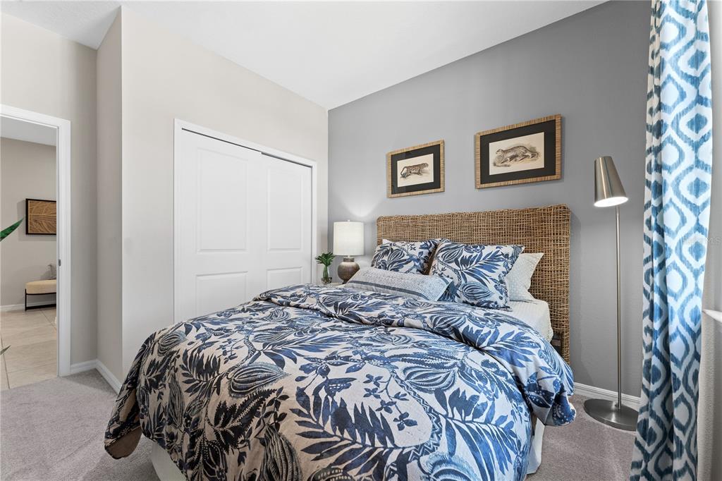 A bedroom features a woven headboard, blue patterned bedding, and a floor lamp — 1710 FLAG STREET, HAINES CITY, FL