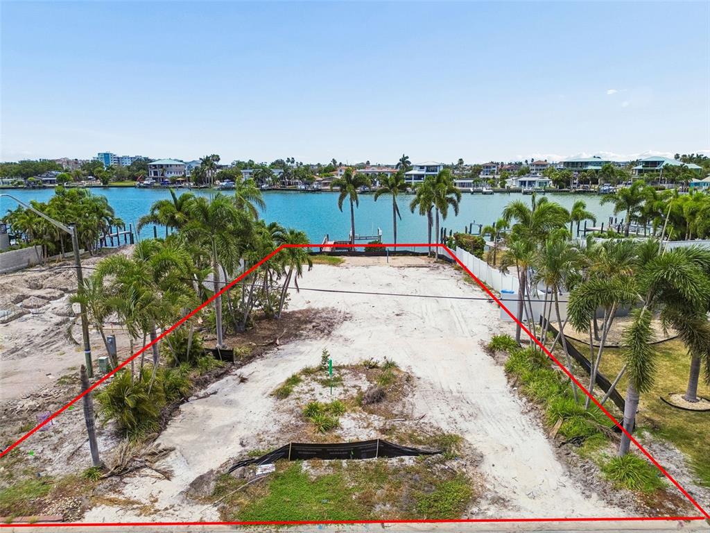 An aerial view shows a vacant waterfront lot outlined in red with palm trees — 10246 TARPON DRIVE, TREASURE ISLAND, FL
