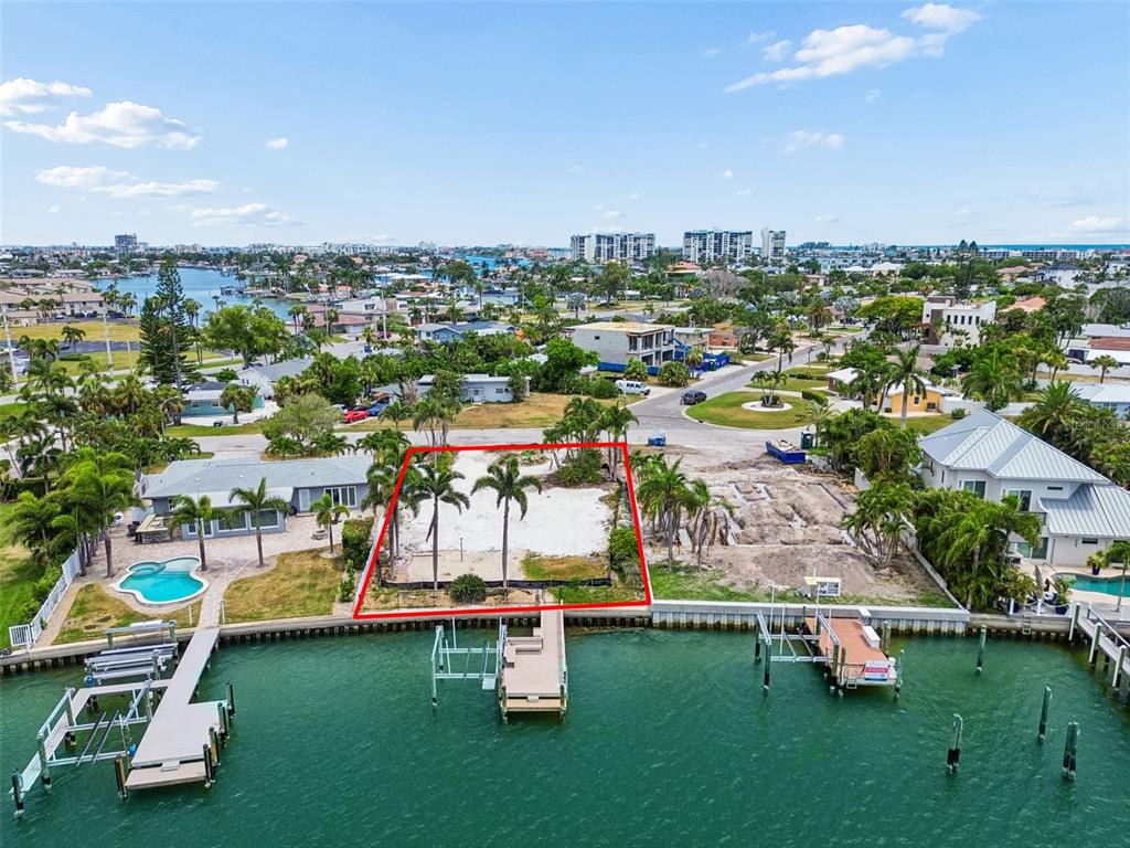 An aerial view shows a vacant waterfront lot outlined in red between two houses — 10246 TARPON DRIVE, TREASURE ISLAND, FL