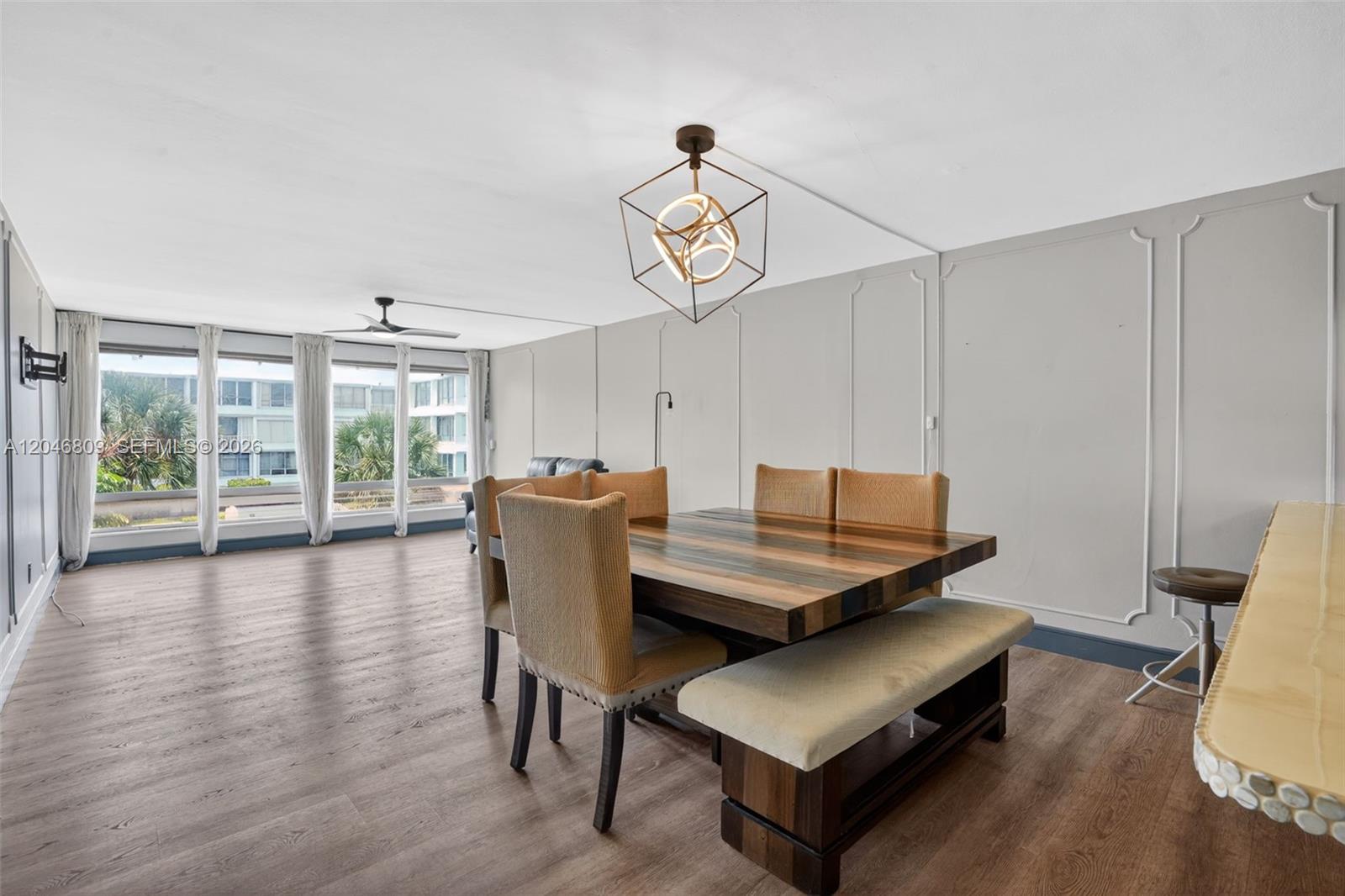 A dining area features a wooden table, upholstered chairs, a bench, and a geometric light fixture — 10240 Collins Ave # 207, Bal Harbour FL 33154, BAL HARBOUR, FL