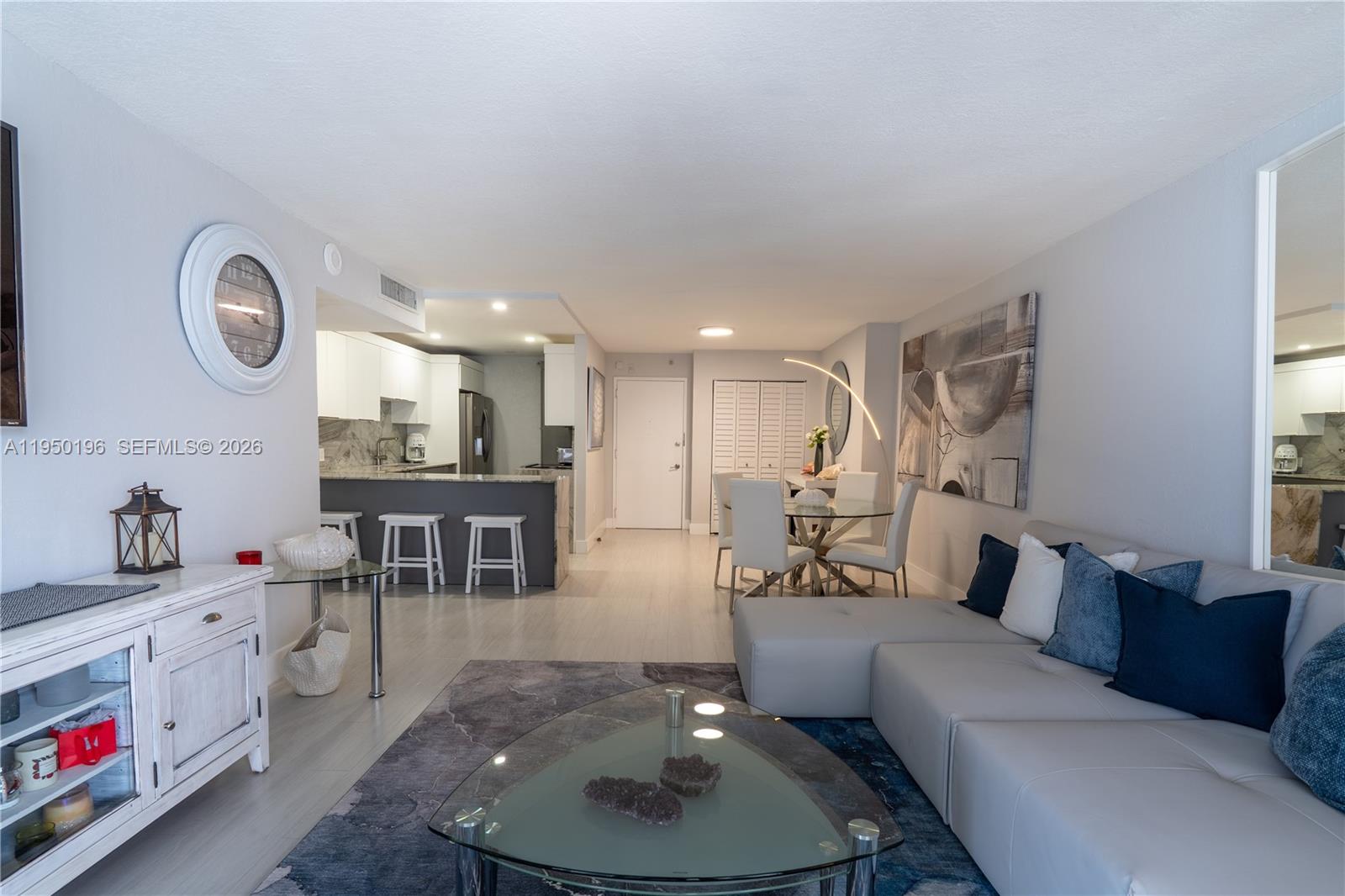 A living room with a sectional sofa, dining area, and kitchen with a breakfast bar — 5701 Collins Ave # 1417, Miami Beach FL 33140, MIAMI BEACH, FL