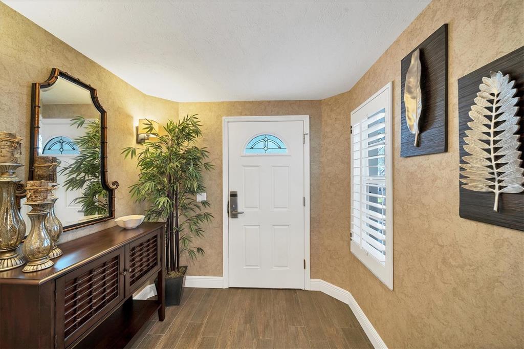 An entryway features a white front door, a dark wood console table, and textured walls — 3401 54TH DRIVE W UNIT 202, BRADENTON, FL
