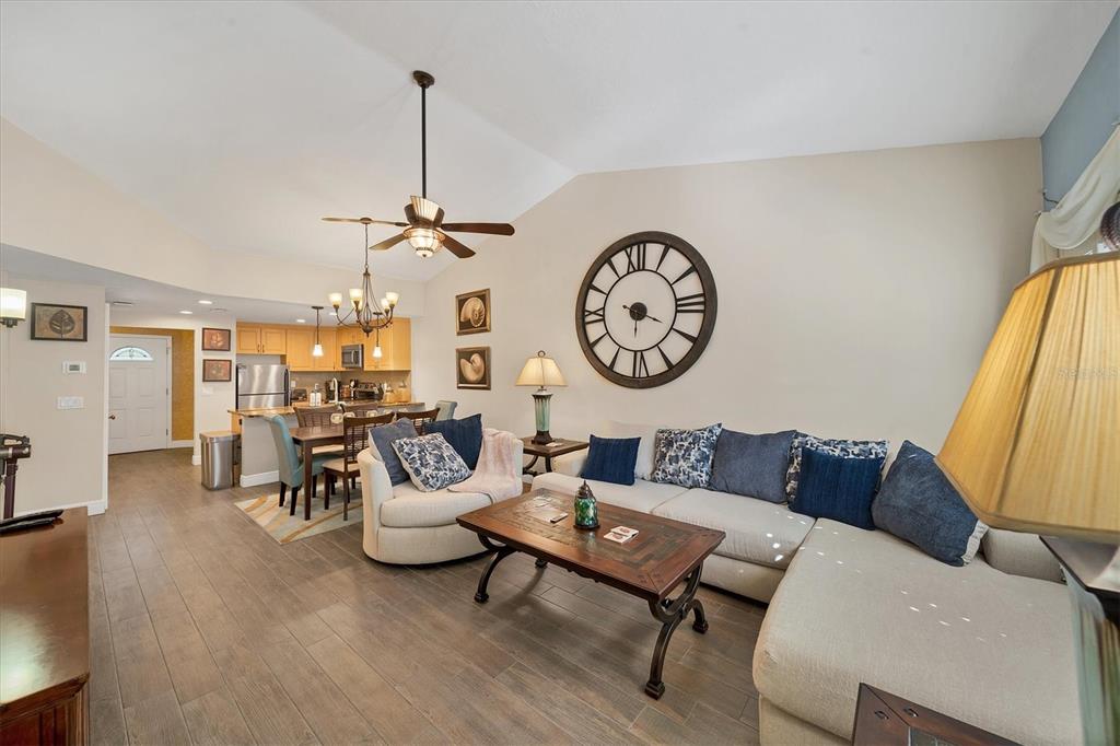 A living room with a sectional sofa, a round chair, and an open-concept kitchen — 3401 54TH DRIVE W UNIT 202, BRADENTON, FL