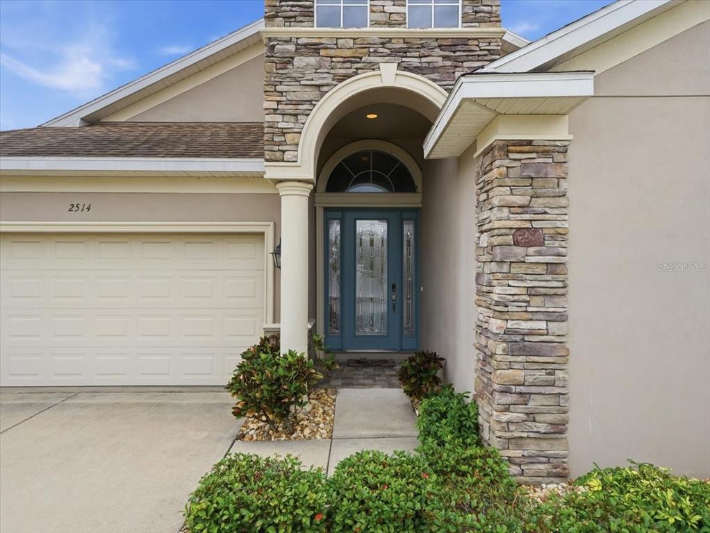 A stone-accented entryway features a blue front door with a glass transom and sidelights — 2514 SUMMERDALE COURT, CLEARWATER, FL