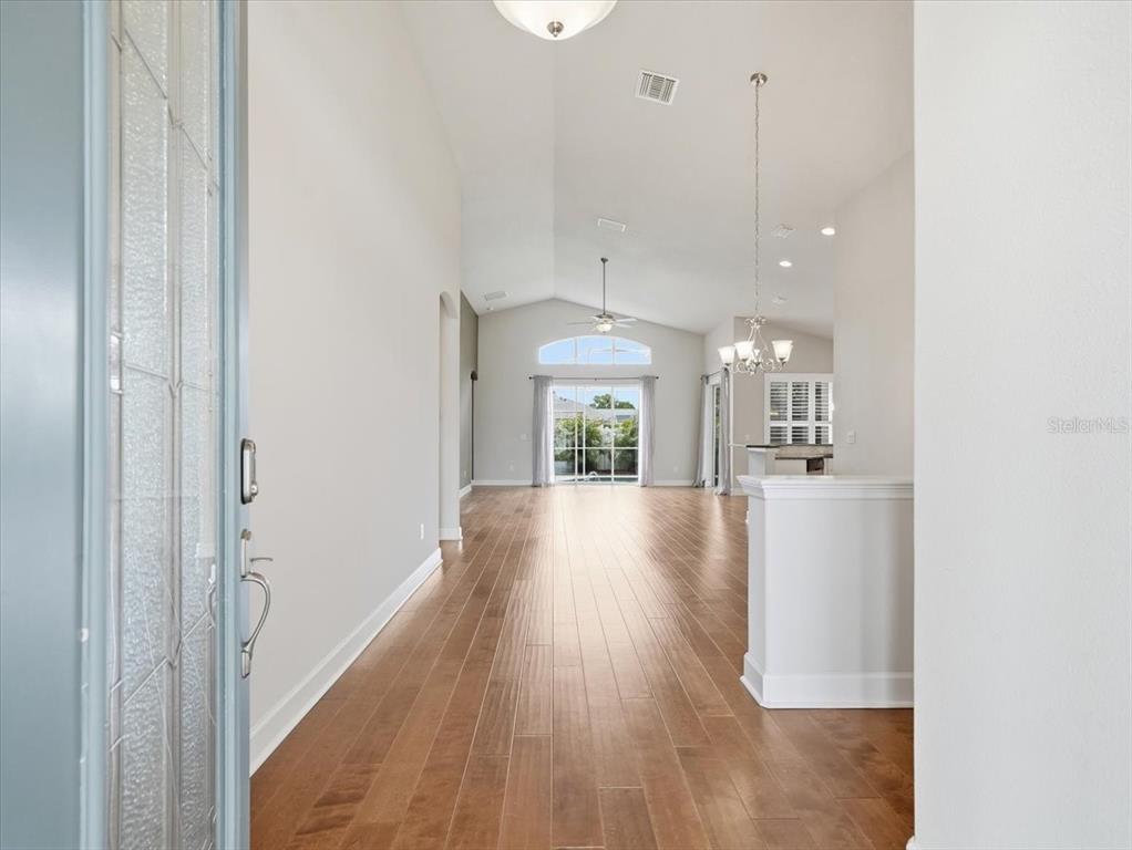 A view from an entryway into a living area with hardwood floors and vaulted ceilings — 2514 SUMMERDALE COURT, CLEARWATER, FL