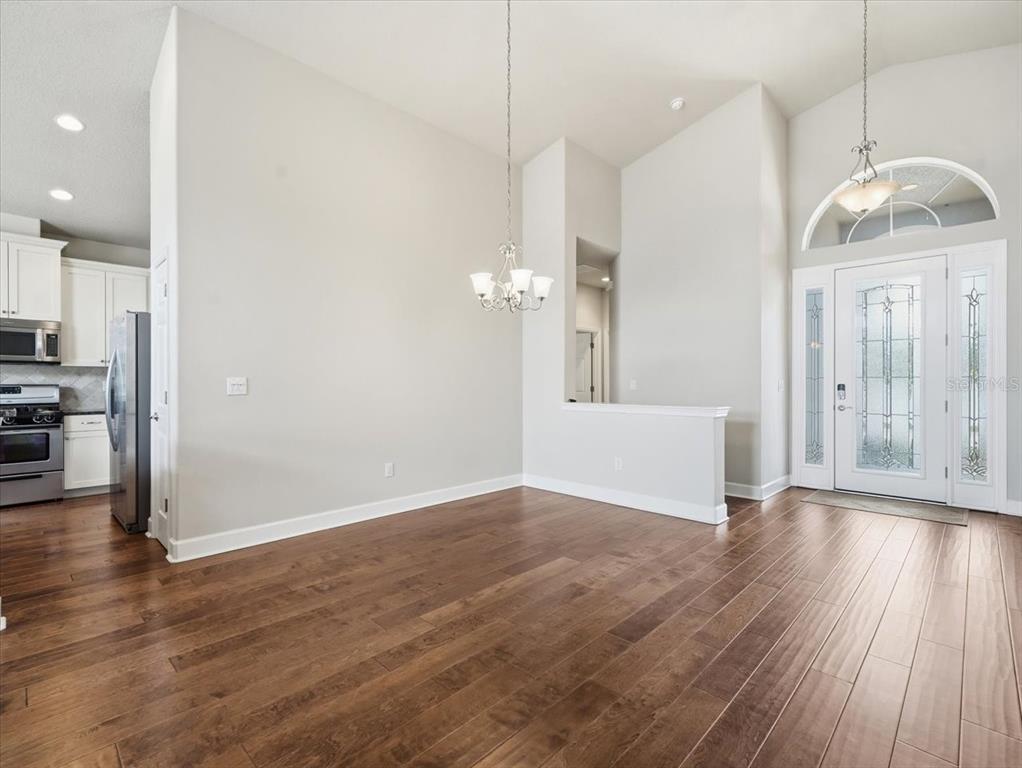 An open dining area with hardwood floors, a chandelier, and an entryway with a glass door — 2514 SUMMERDALE COURT, CLEARWATER, FL
