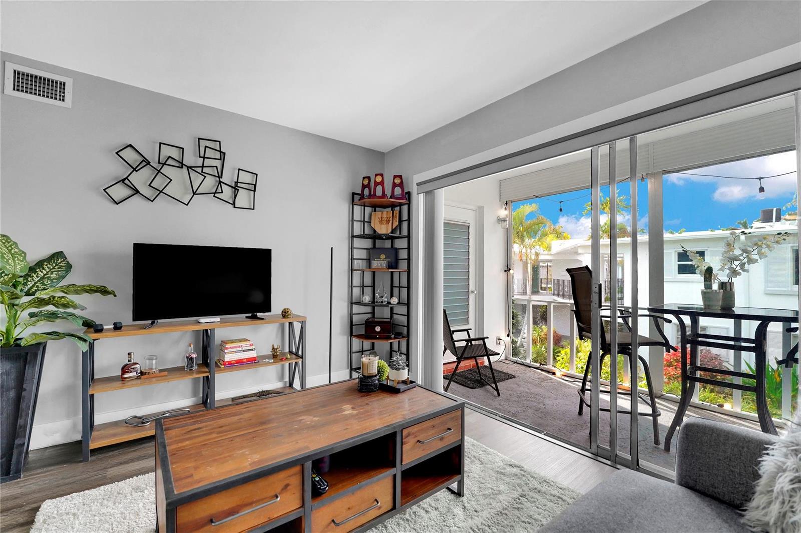 A living room with a television, wooden coffee table, and sliding doors leading to a balcony — 2161 NE 42nd Court # 215, Lighthouse Point FL 33064, LIGHTHOUSE POINT, FL
