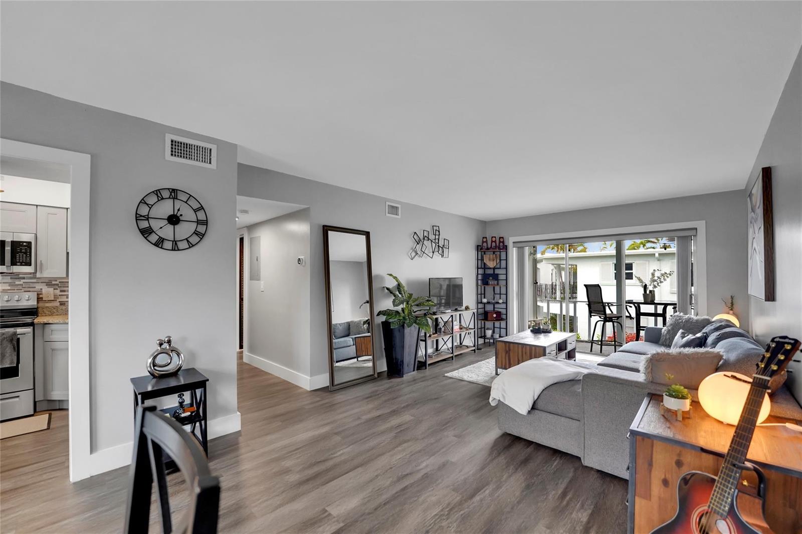 A living room with gray walls, wood-look flooring, a sectional sofa, and a sliding glass door — 2161 NE 42nd Court # 215, Lighthouse Point FL 33064, LIGHTHOUSE POINT, FL