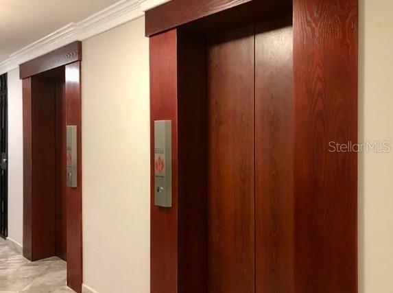 Two elevator doors with wood-paneled frames are set into a white wall — 76 KINGS COURT STREET UNIT 902, SAN JUAN, PR
