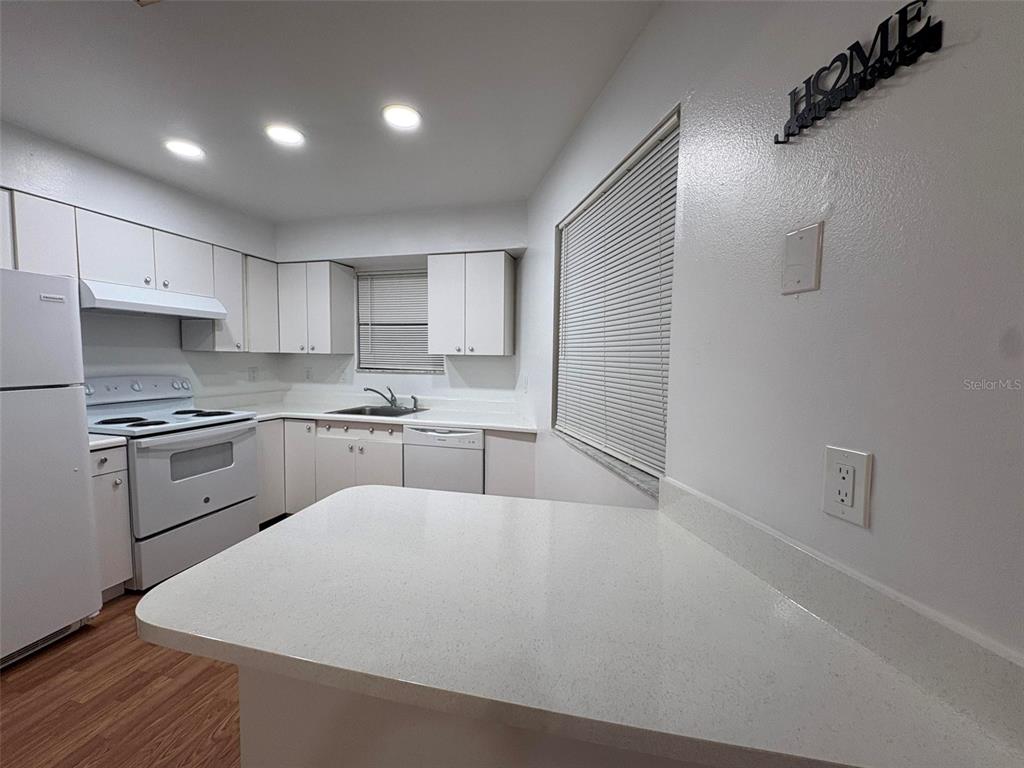 A kitchen features white cabinets, white appliances, and a white countertop breakfast bar — 1724 FOXHALL CIRCLE UNIT 1724, KISSIMMEE, FL