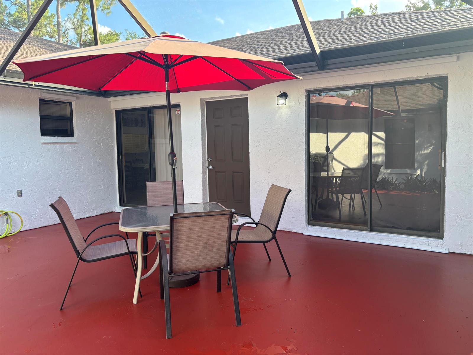 A patio with a red floor, a table with four chairs, and a red umbrella — 1289 Periwinkle Place, Wellington FL 33414, WELLINGTON, FL