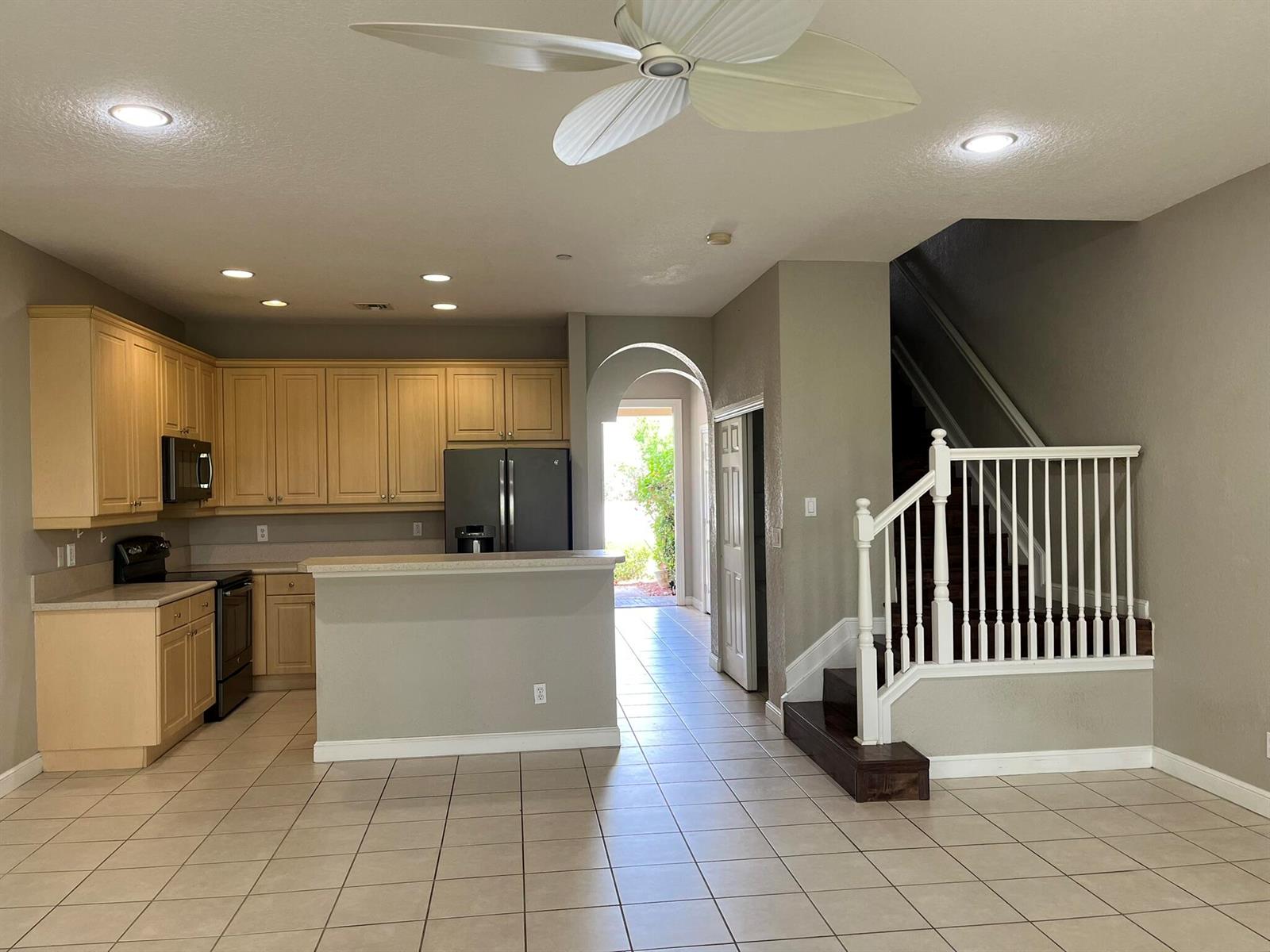 A kitchen with light wood cabinets, a breakfast bar, and stairs leading to an upper level — 404 SE Bloxham Way, Stuart FL 34997, STUART, FL