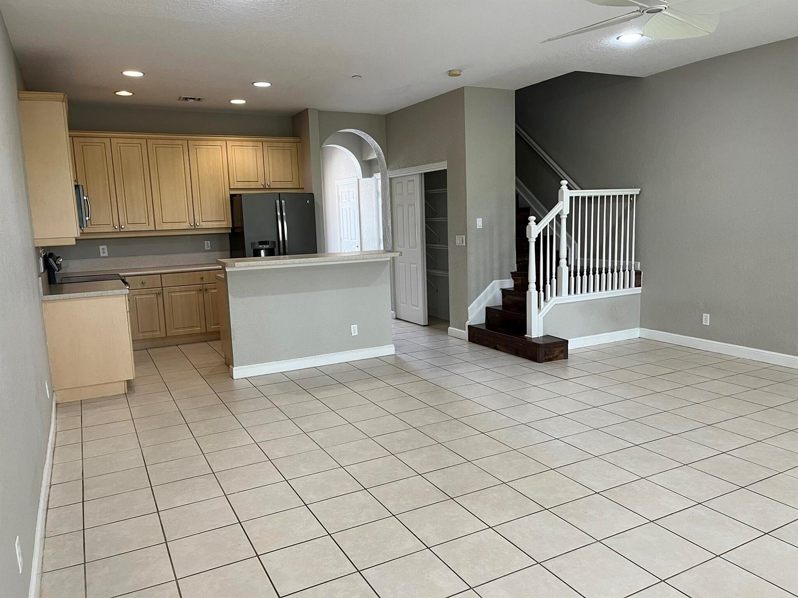 A kitchen with light wood cabinets and a breakfast bar opens to a tiled living area — 404 SE Bloxham Way, Stuart FL 34997, STUART, FL