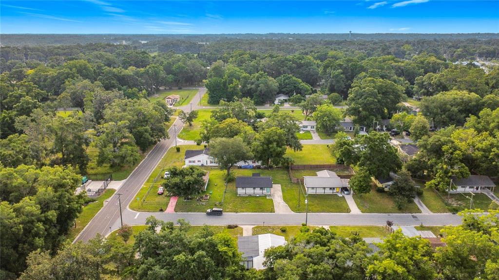 An aerial view shows a residential neighborhood with several houses surrounded by trees and roads — 1504 NW 19TH COURT, OCALA, FL