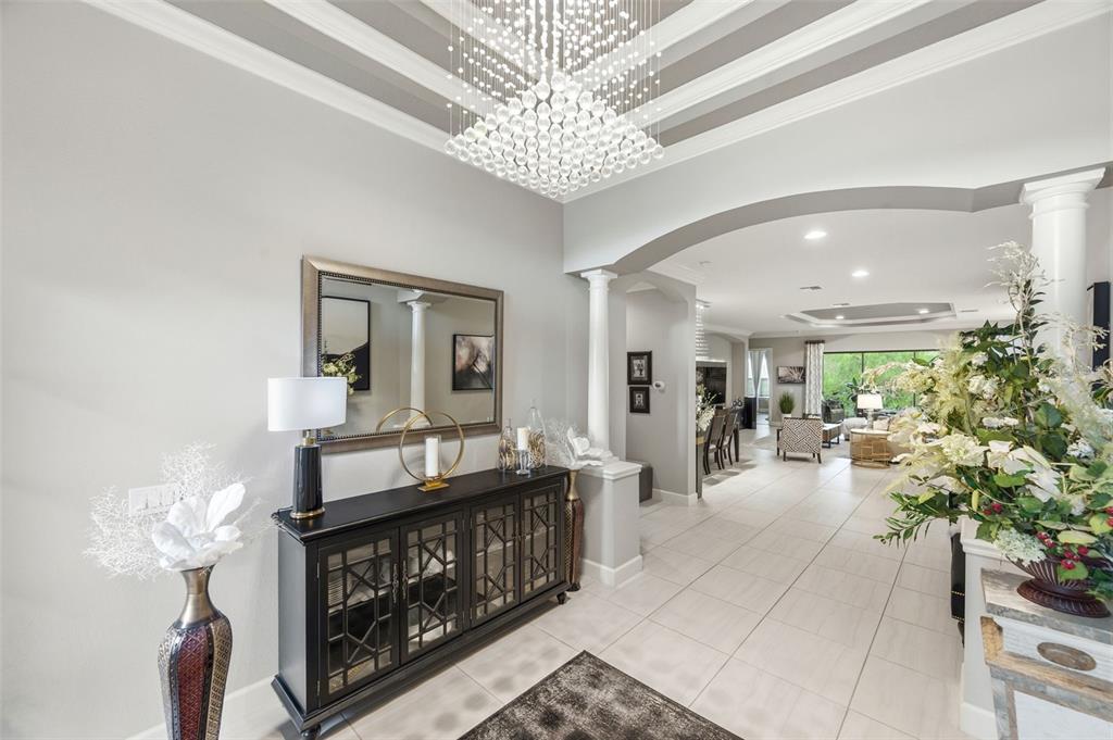 A bright foyer features a crystal chandelier, tiled floors, and a black console table — 20117 UMBRIA HILL DRIVE, TAMPA, FL