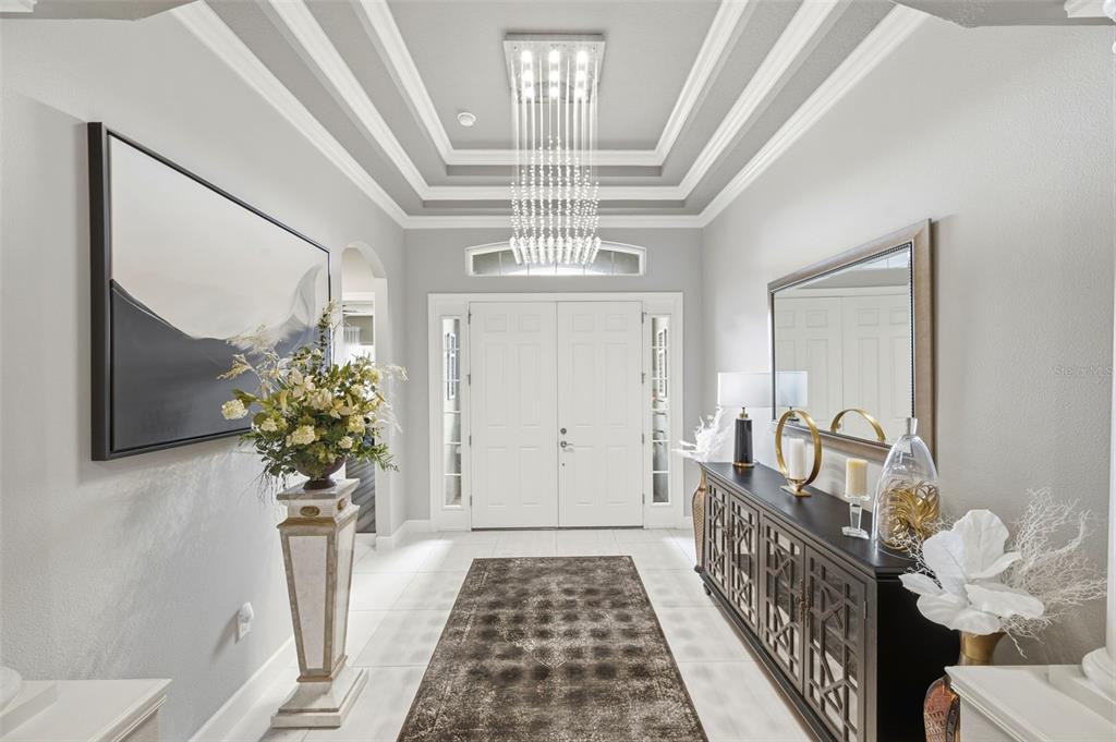 A bright entryway features a crystal chandelier, a tray ceiling, and a dark console table — 20117 UMBRIA HILL DRIVE, TAMPA, FL