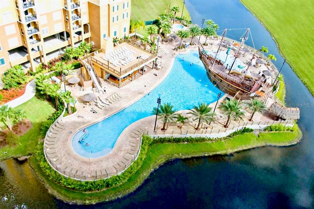 An aerial view shows a resort swimming pool featuring a large pirate ship play structure — 8113 RESORT VILLAGE DRIVE UNIT 4404, ORLANDO, FL