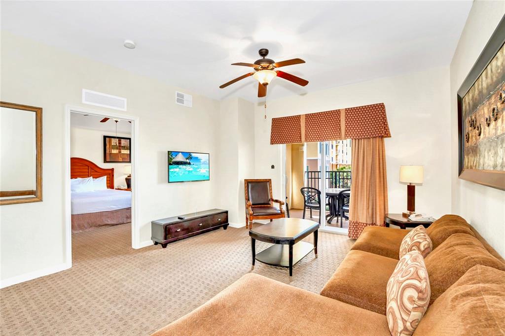 A living room with a brown sectional sofa, ceiling fan, and a view into a bedroom — 8113 RESORT VILLAGE DRIVE UNIT 4404, ORLANDO, FL