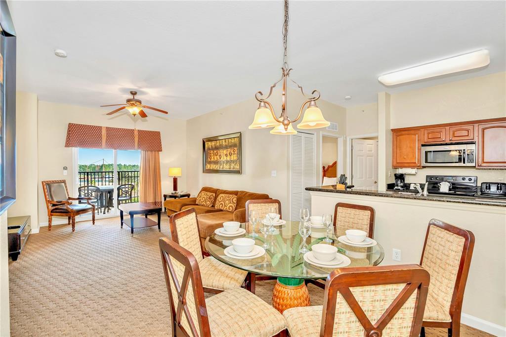 A dining area with a glass table sits in front of an open kitchen and living room — 8113 RESORT VILLAGE DRIVE UNIT 4404, ORLANDO, FL