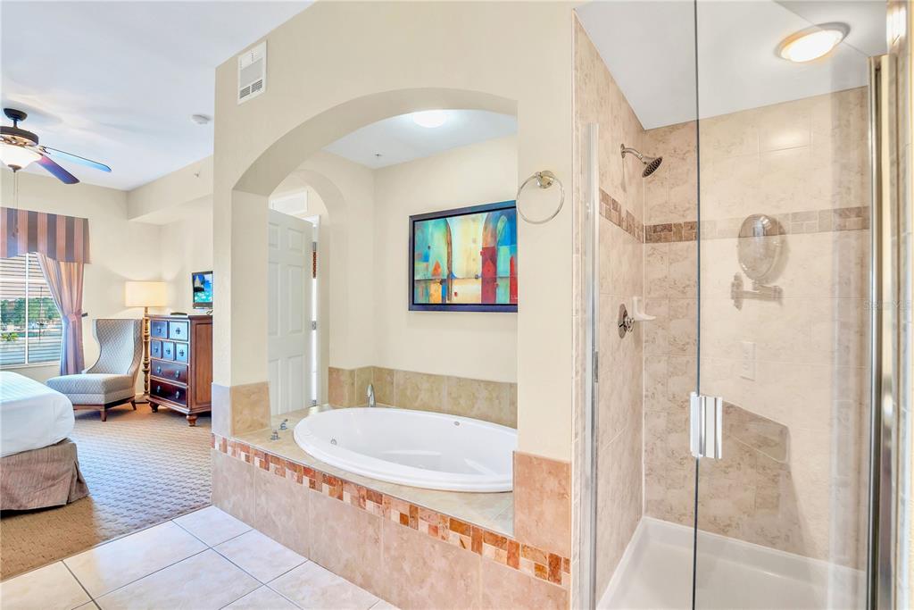 A bathroom features a jetted tub in an arched alcove next to a glass shower — 8113 RESORT VILLAGE DRIVE UNIT 4404, ORLANDO, FL