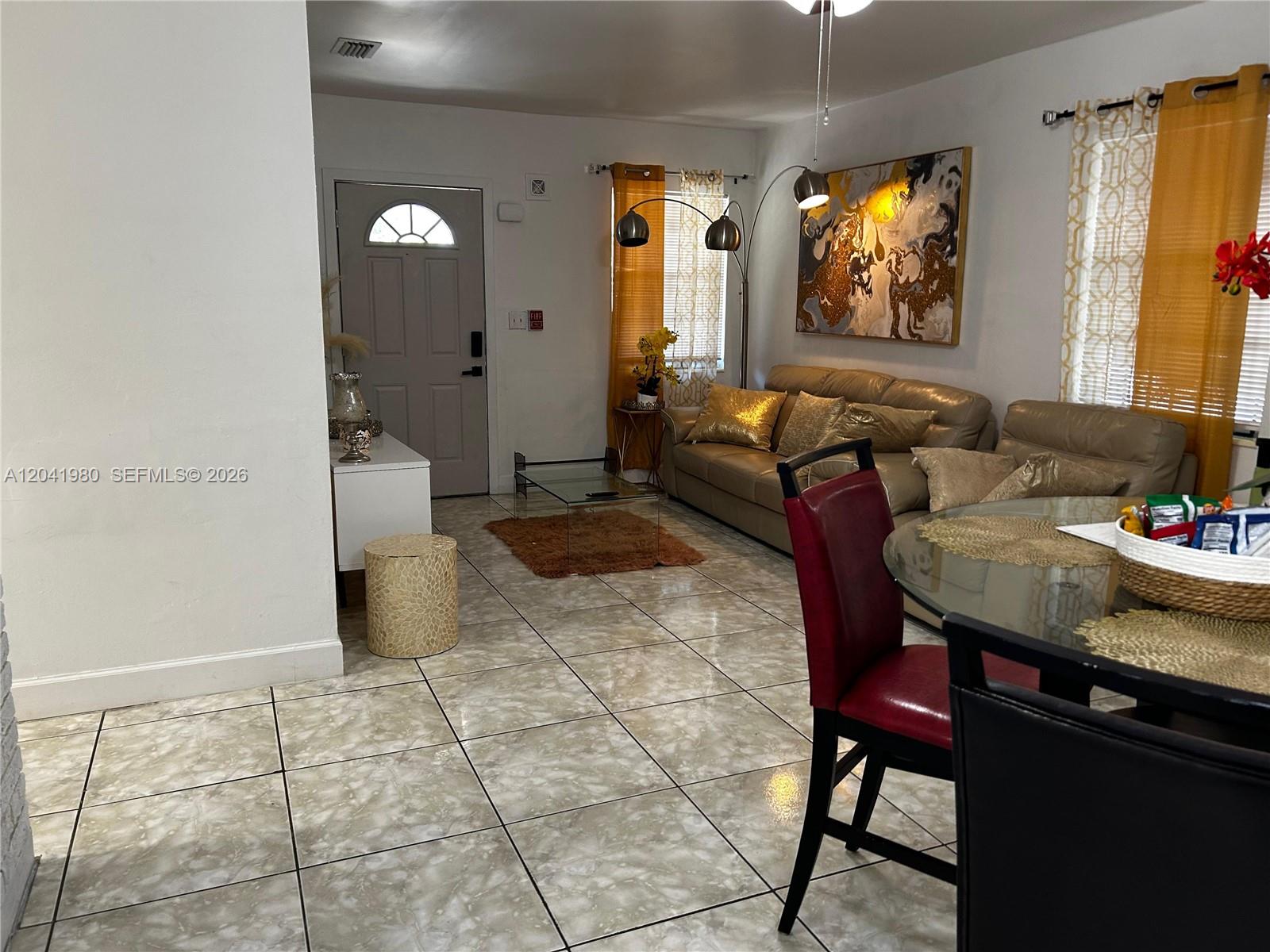 A living and dining area features tiled floors, a beige sofa, and a glass table — 295 NW 189th Ter, Miami Gardens FL 33169, MIAMI GARDENS, FL
