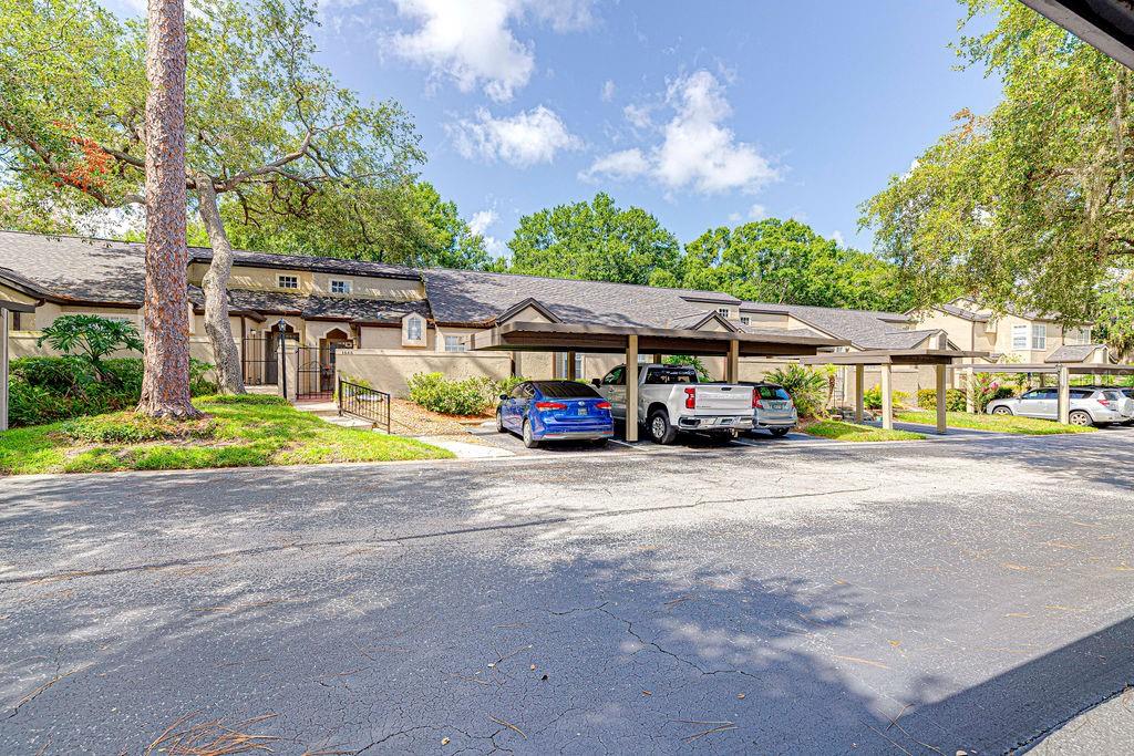 A residential building exterior features a covered parking area with several cars parked underneath — 1545 FARRINDON CIRCLE UNIT 1545, LAKE MARY, FL