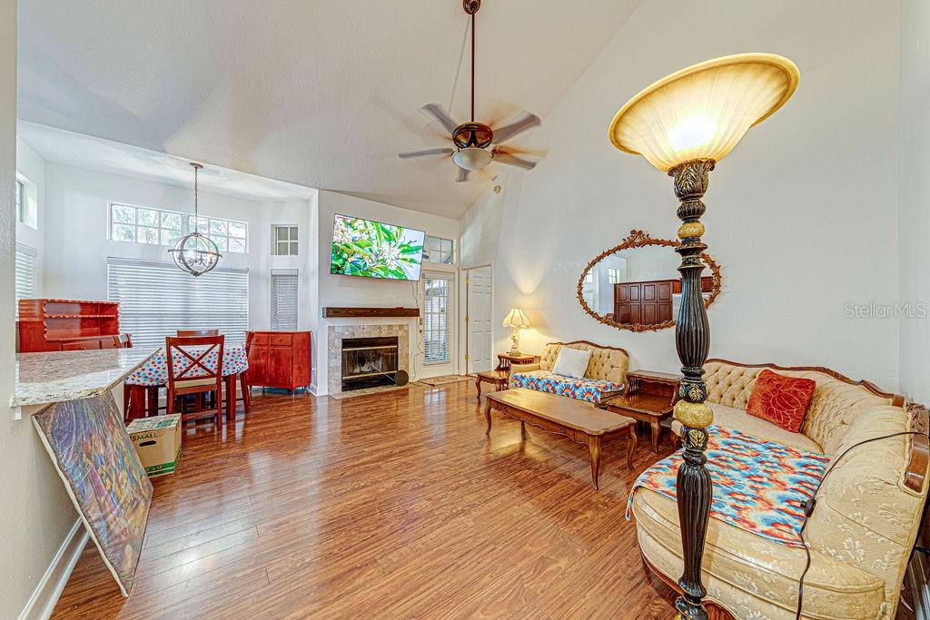 A living room and dining area with wood flooring, a fireplace, and vaulted ceilings — 1545 FARRINDON CIRCLE UNIT 1545, LAKE MARY, FL