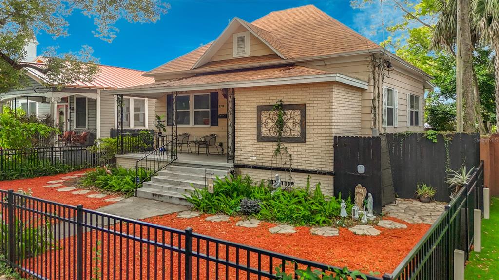 A single-story house with a brick facade, front porch, and a fenced yard with mulch — 2708 N JEFFERSON STREET, TAMPA, FL
