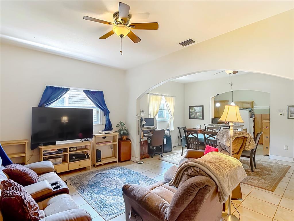 A living room with tile floors, a ceiling fan, and an arched opening to a kitchen — 2708 N JEFFERSON STREET, TAMPA, FL
