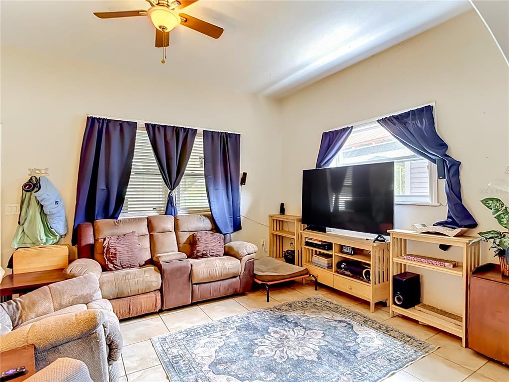 A living room features a brown reclining sofa, a television on a stand, and tile flooring — 2708 N JEFFERSON STREET, TAMPA, FL