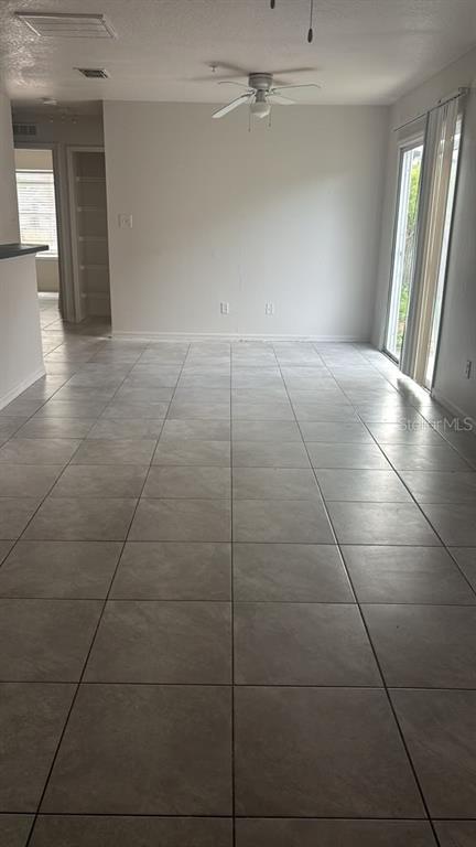 An empty room with light-colored tile flooring, a ceiling fan, and a sliding glass door — 1317 FETTLER WAY, WINTER GARDEN, FL