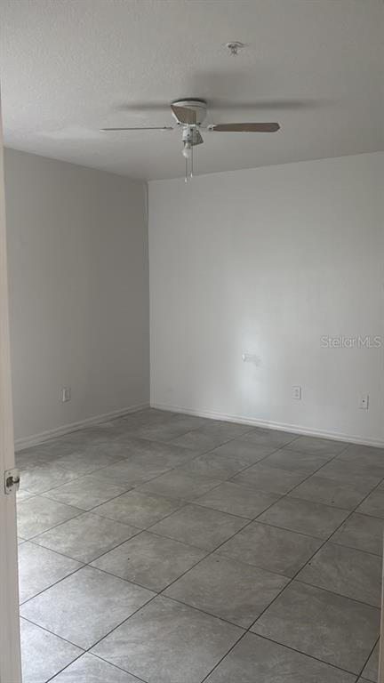 An empty room with light gray walls, a ceiling fan, and large square floor tiles — 1317 FETTLER WAY, WINTER GARDEN, FL