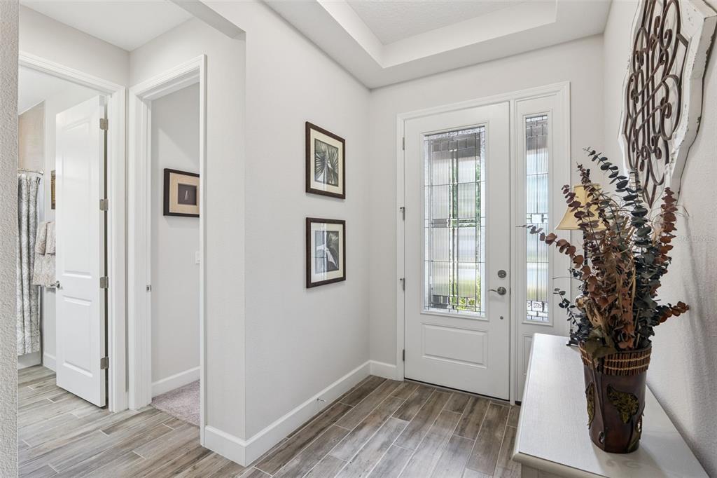 An entryway with wood-look tile flooring, a white front door, and two framed wall pictures — 1157 AVERY MEADOWS WAY, DELAND, FL