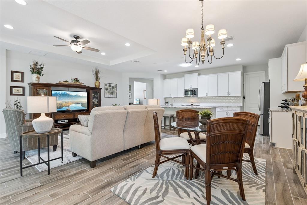 An open-concept living and dining area features white cabinetry, tile flooring, and a chandelier — 1157 AVERY MEADOWS WAY, DELAND, FL