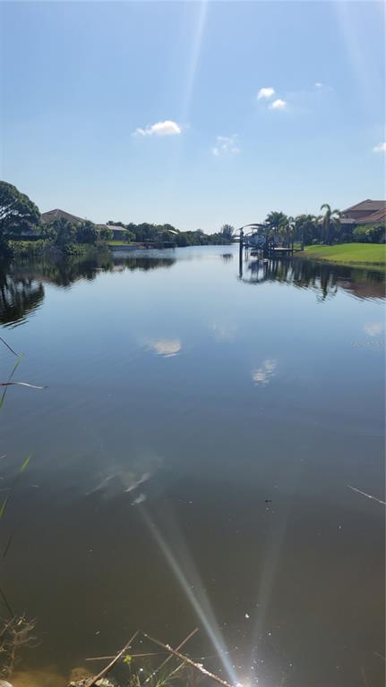 A view of a calm canal bordered by residential homes, docks, and lush green landscaping — 14718 LILLIAN CIRCLE, PORT CHARLOTTE, FL